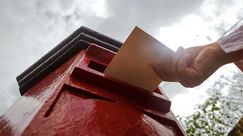 A person placing a letter into postal box.