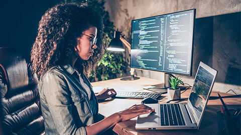 A developer coding in their preferred IDE, on their laptop and additional displays