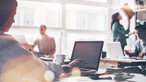 Over-the-shoulder view of a designer checking software setup on her laptop