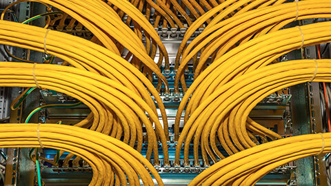 A bunch of cables going into the back of a stack of network boxes