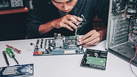 A technician working on a motherboard with various tools