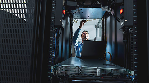 A wide shot of a network administrator working in a server room