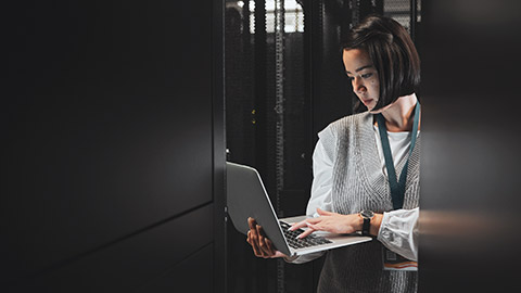 A person in a server room with a laptop