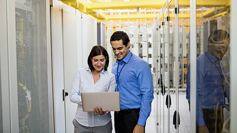 Technicians discussing over laptop in server room