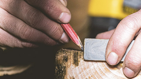 A close view of a carpenter measuring a piece of wood before cutting it