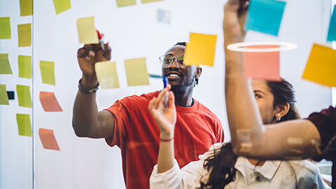 A design team planning an app using sticky notes on a glass wall