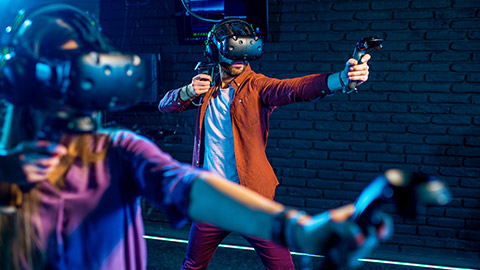 Two people playing a game using VR goggles and controllers