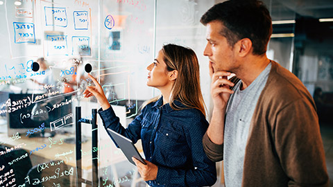 2 developers mapping out a project on a glass wall