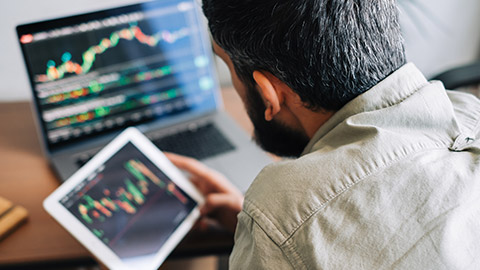 An over-the-shoulder view of an analyst working on multiple devices