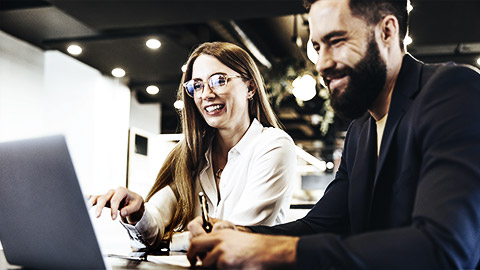 Two people looking happily at a laptop