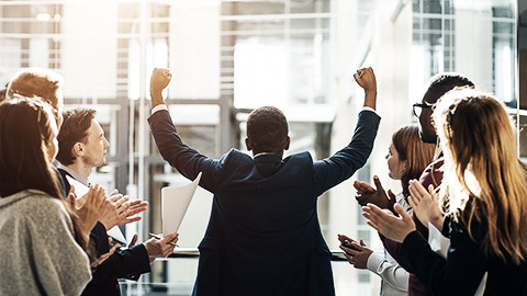 A truimphant person being cheered on by colleagues