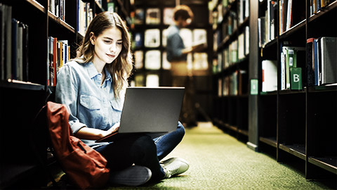 A person reading on their laptop in a library