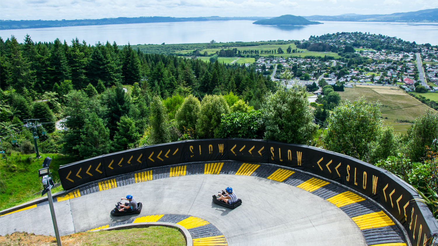 View of two cars at Skyline Luge Rotorua with lake and island in the background