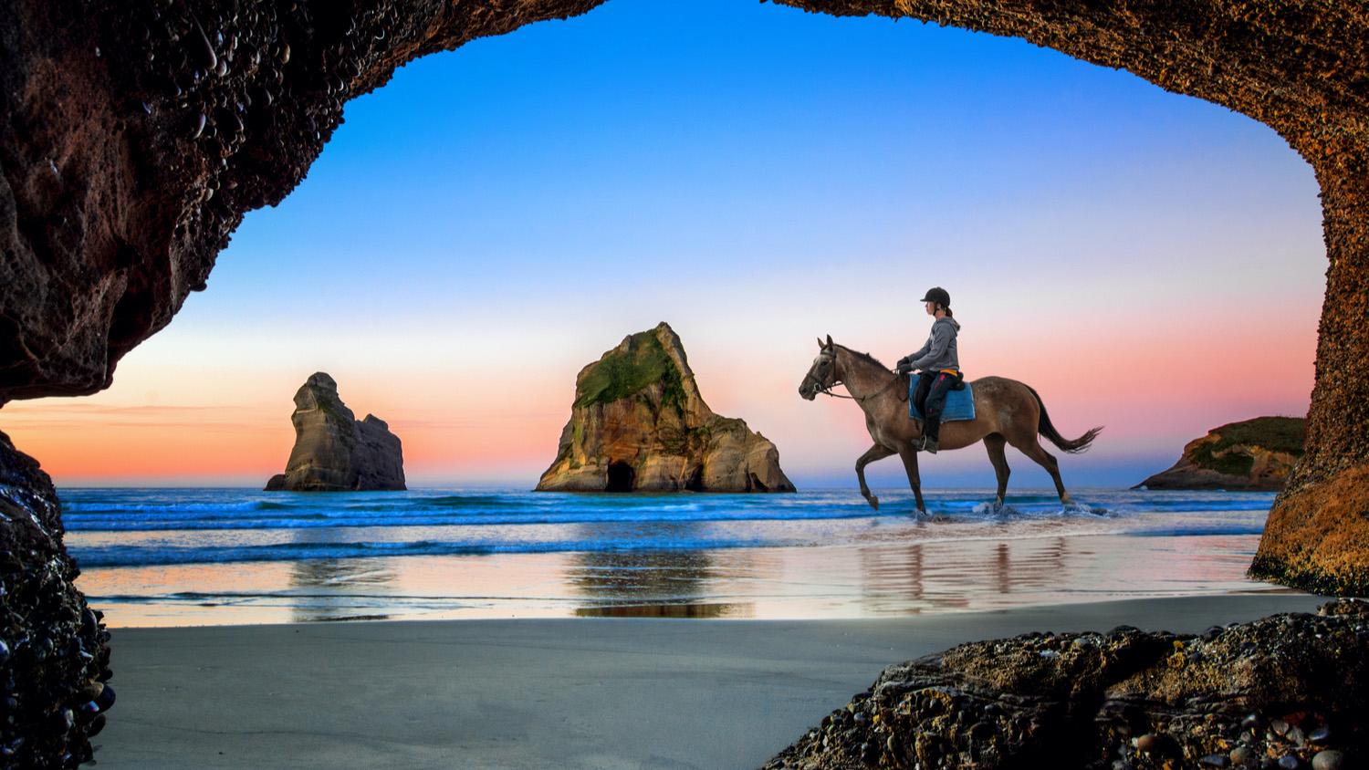 View from the cave of Wharariki Beach with house rider, the place popular for tourist travel in summer.