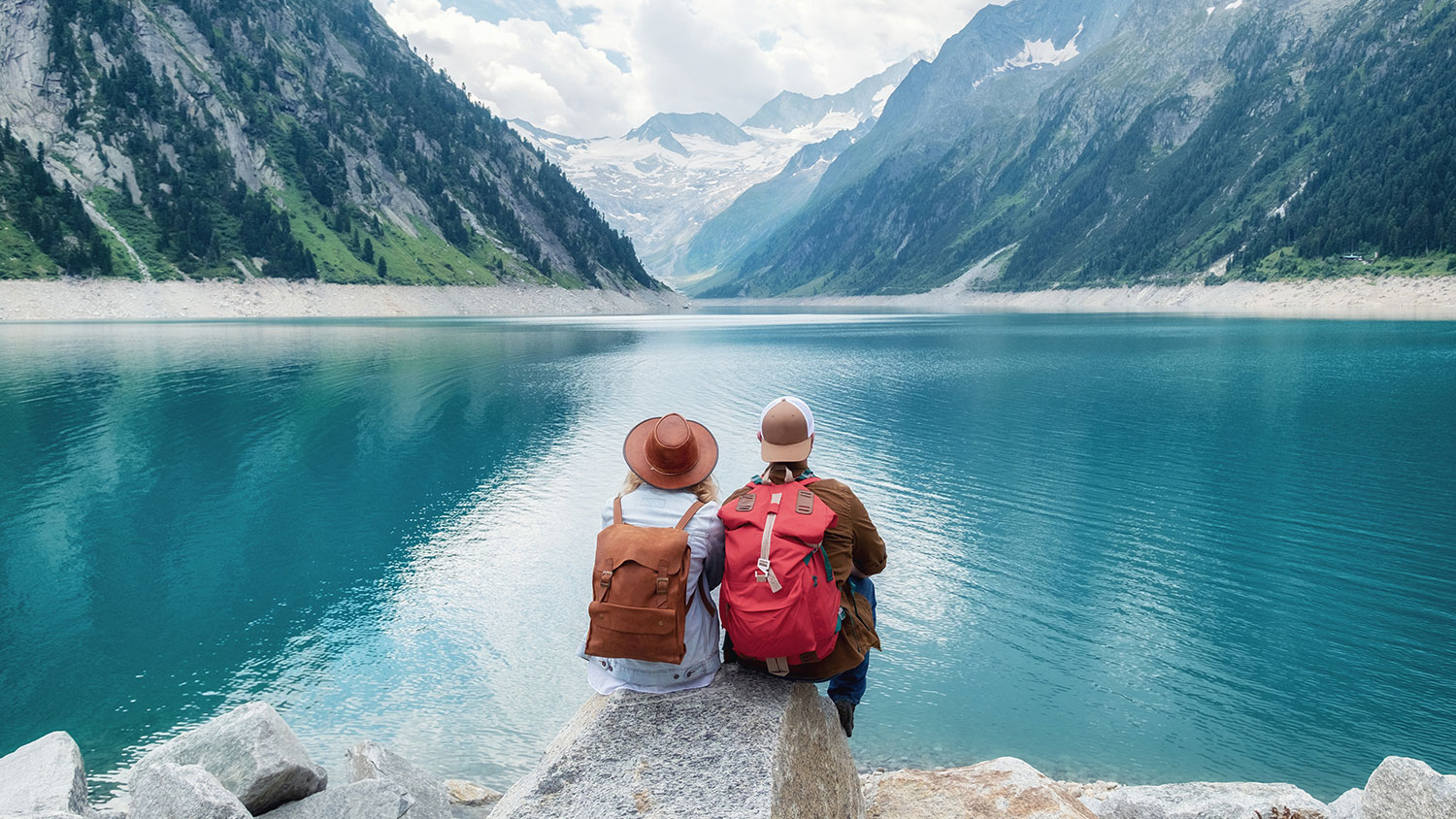 Travelers couple look at the mountain lake. Travel and active life concept with team. Adventure and travel in the mountains region in the Austria