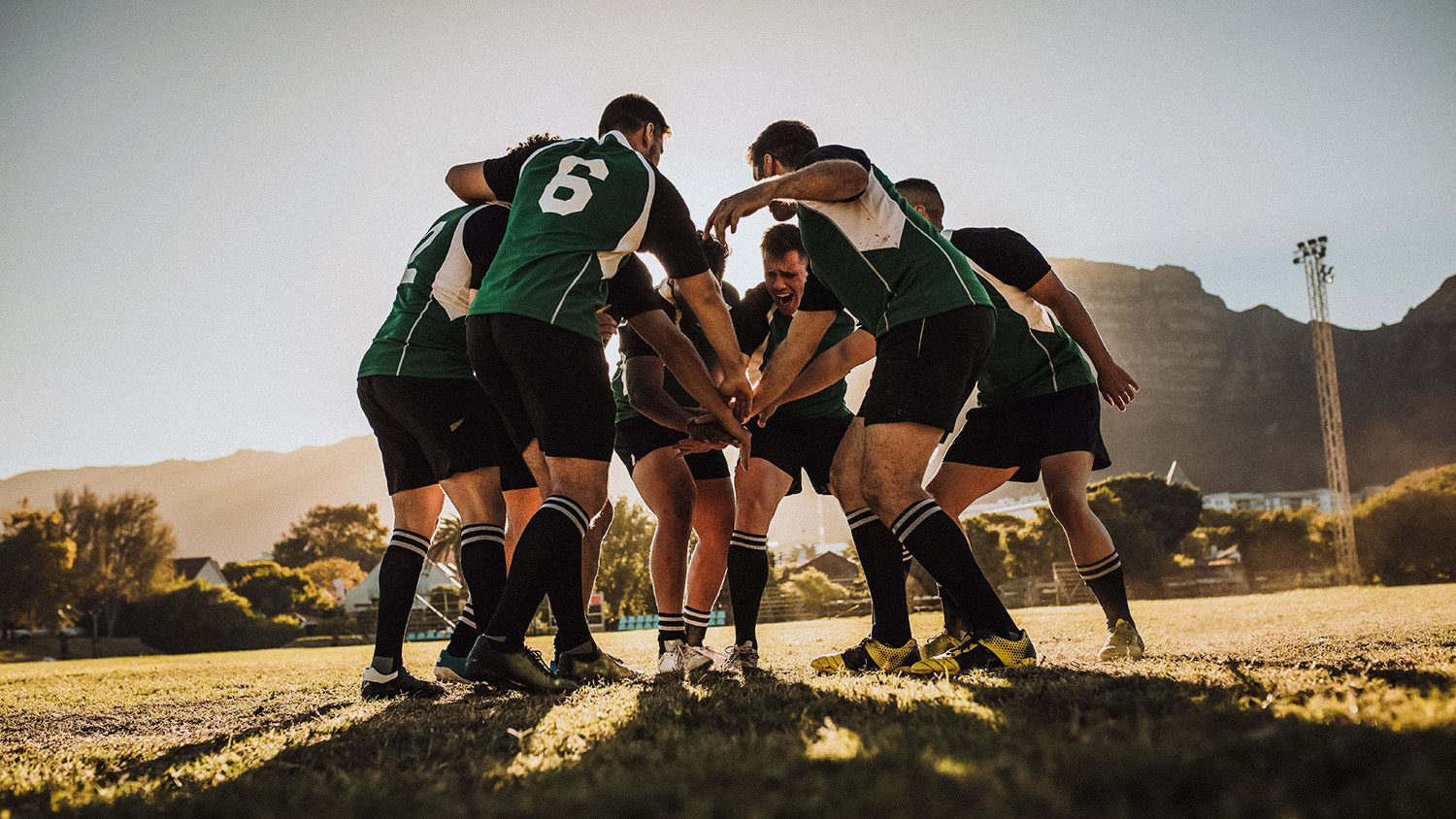 Rugby team putting their hands together after victory. Rugby players cheering and celebrating win.