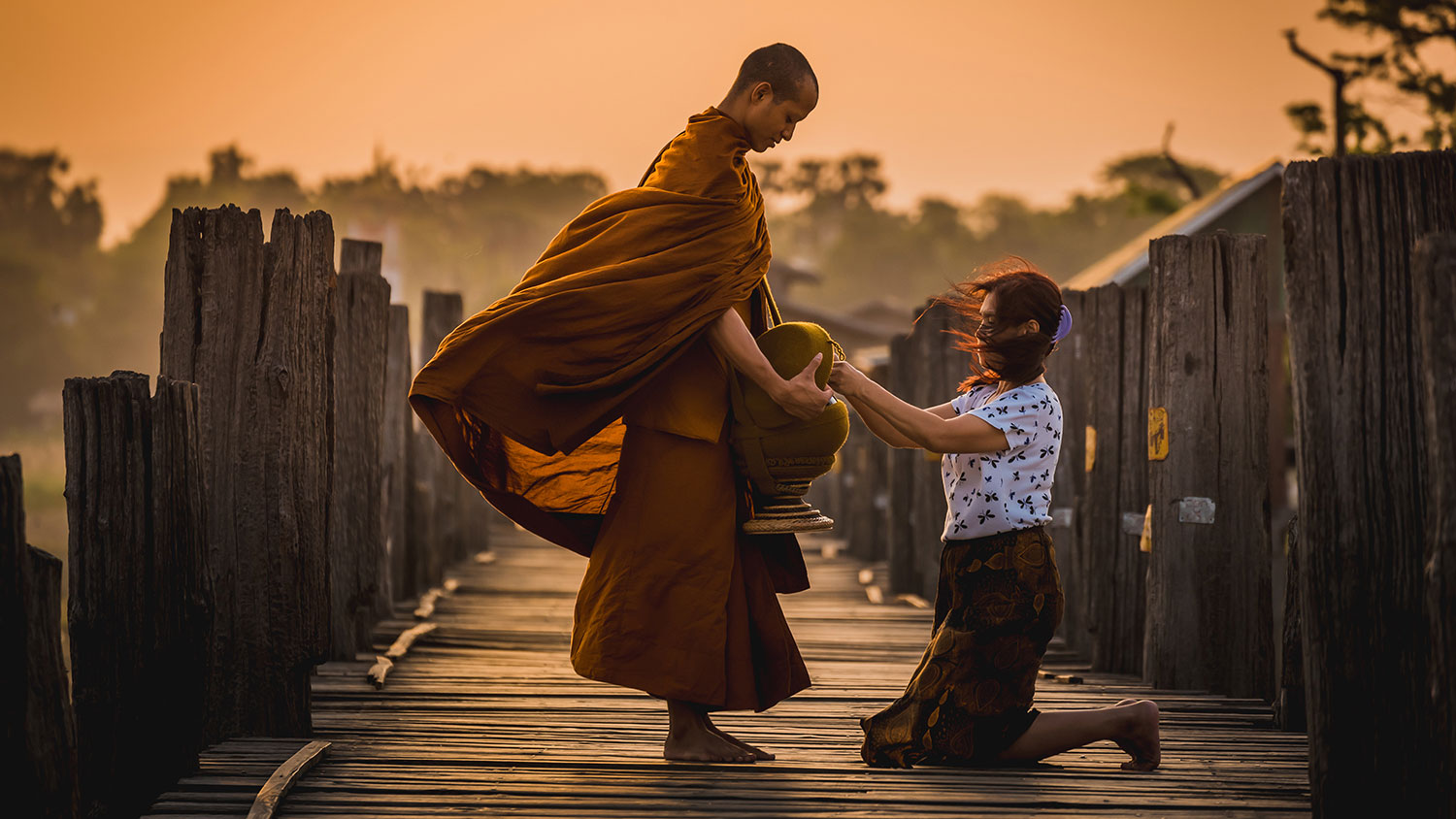 Knelling lady giving food to monk in early morning to pay respect to Buddha