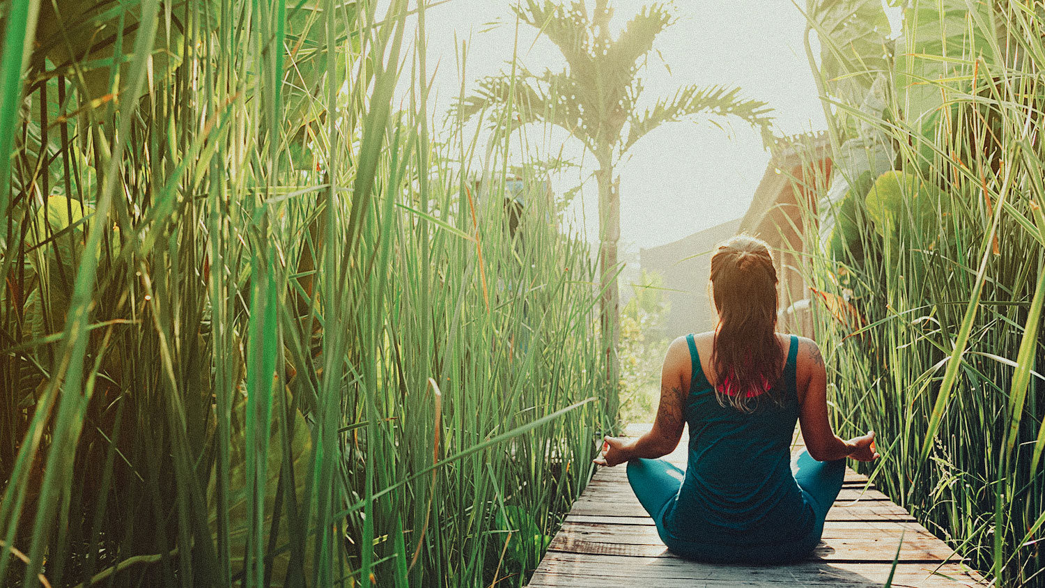 Young woman practicing yoga during luxury yoga retreat in Asia, Bali, meditation, relaxation, getting fit, enlightening, green grass jungle background