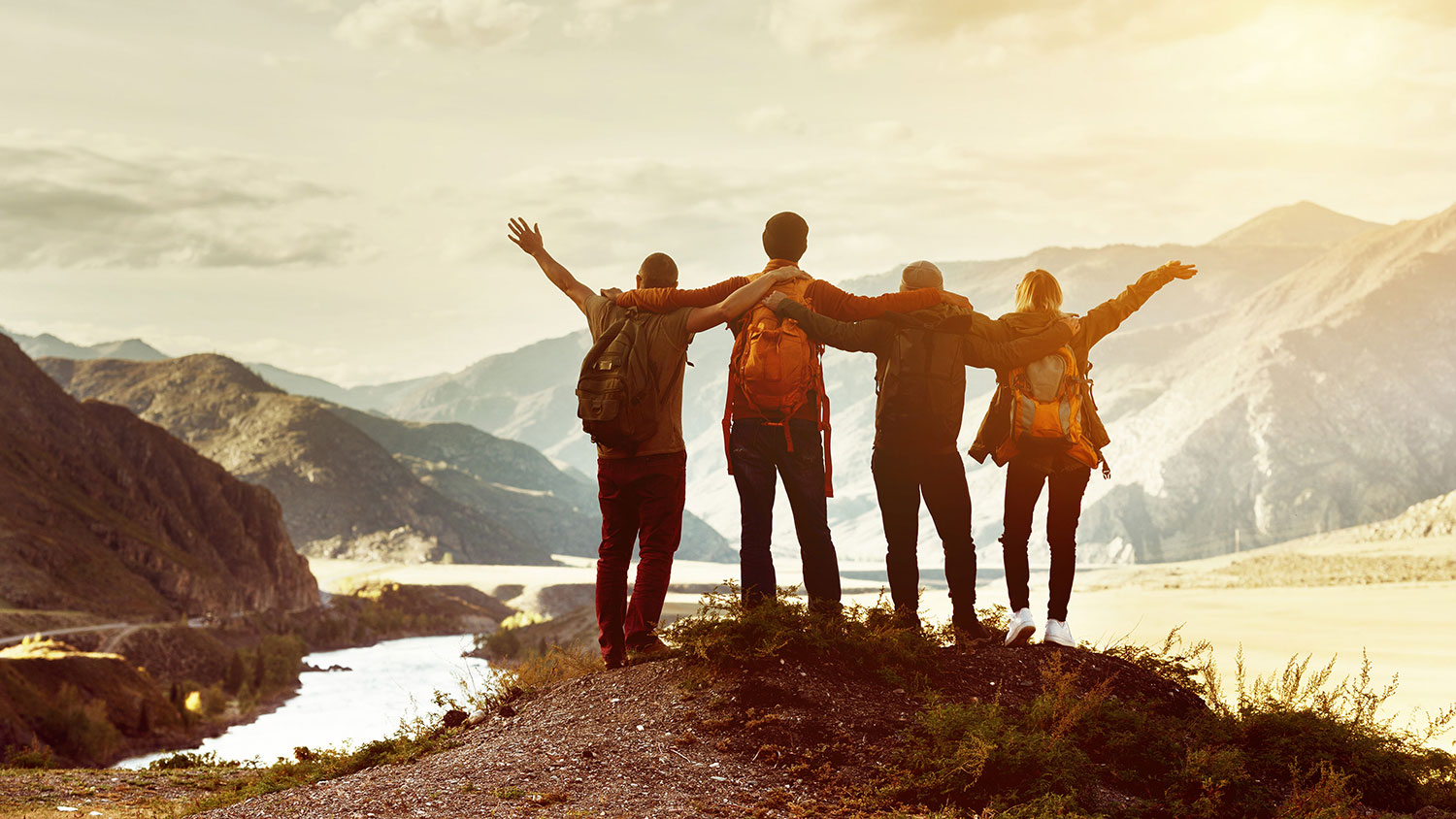 Four happy friends are looking on mountains and having fun together.