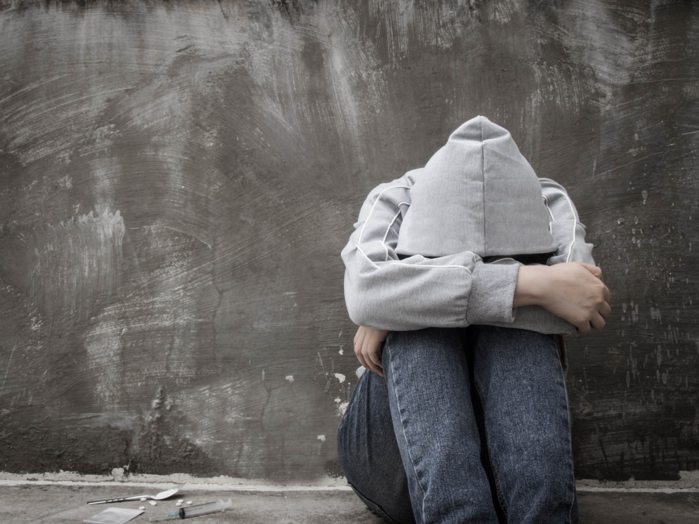 Depressed and hopeless teenage girl sitting alone after using drugs and drunk alcohol at abandoned house