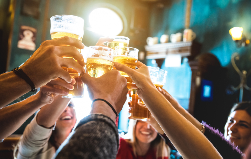 group of happy friends drinking and toasting beer at brewery bar restaurant