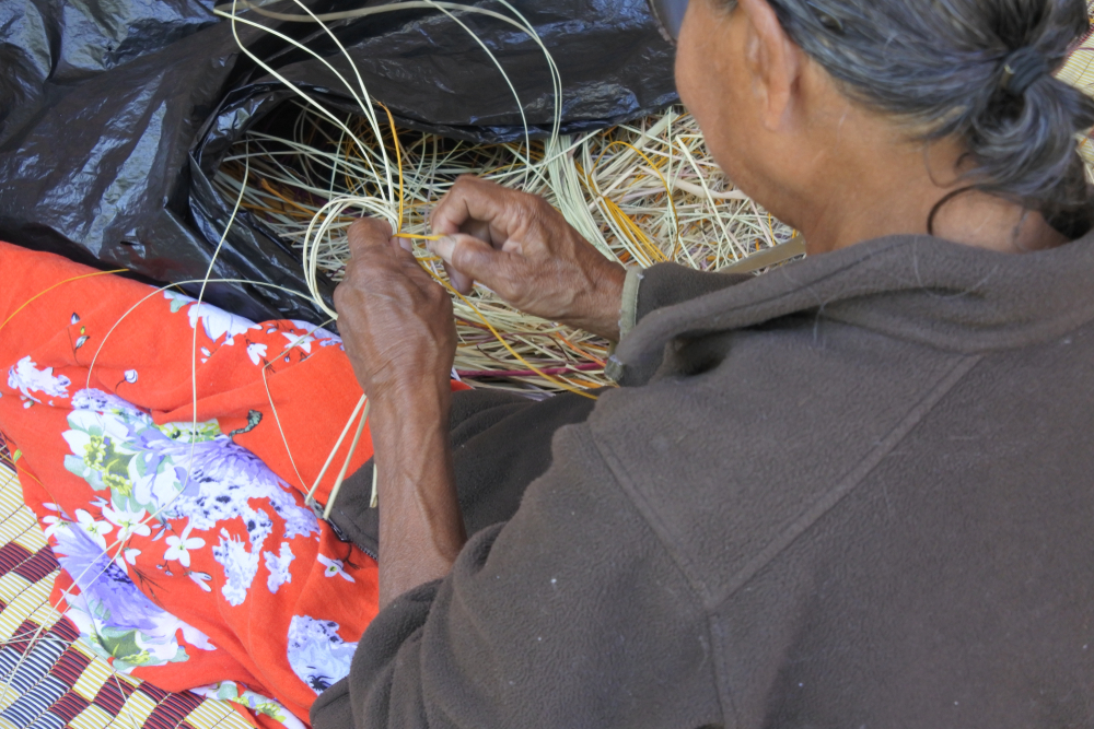 An unrecognizable Indigenous Australian Aboriginal woman basket weaving in Arnhem Land in the Northern Territory of Australia