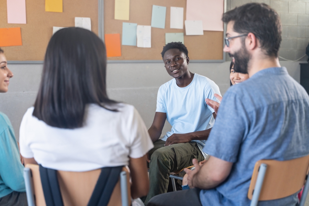 Student talking with teacher and classmates