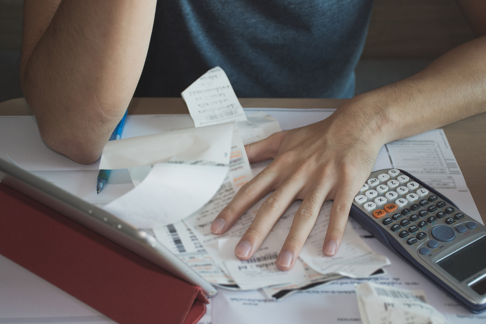 stressed man shocked with amount to be paid for electricity, financial problem. close of photo of hands on bills