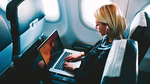 Female professional working on laptop while traveling on a plane