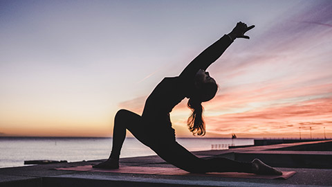 Woman doing yoga at sunrise