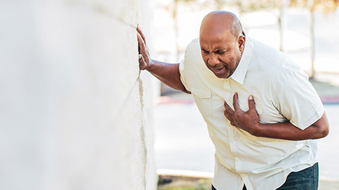 Mature male gripping his chest and possibly having a heart attack