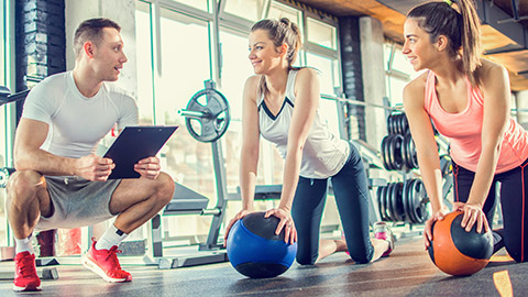 Young male trainer talking to 2 female clients