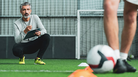 Mature male coach watching athlete perform drills