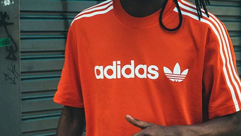 Man wearing bright red Adidas t-shirt while standing outside