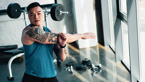 male stretching arm at gym