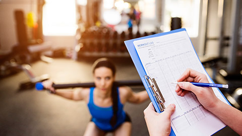 trainer with clipboard watching client