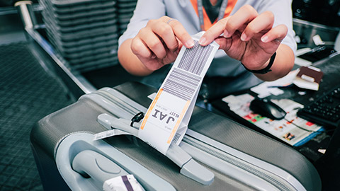 close shot of checkin agent putting luggage tag on bag