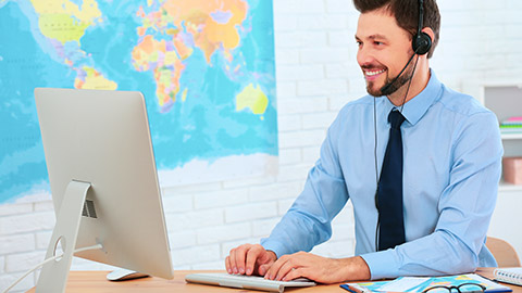 man working at a computer in a travel agency