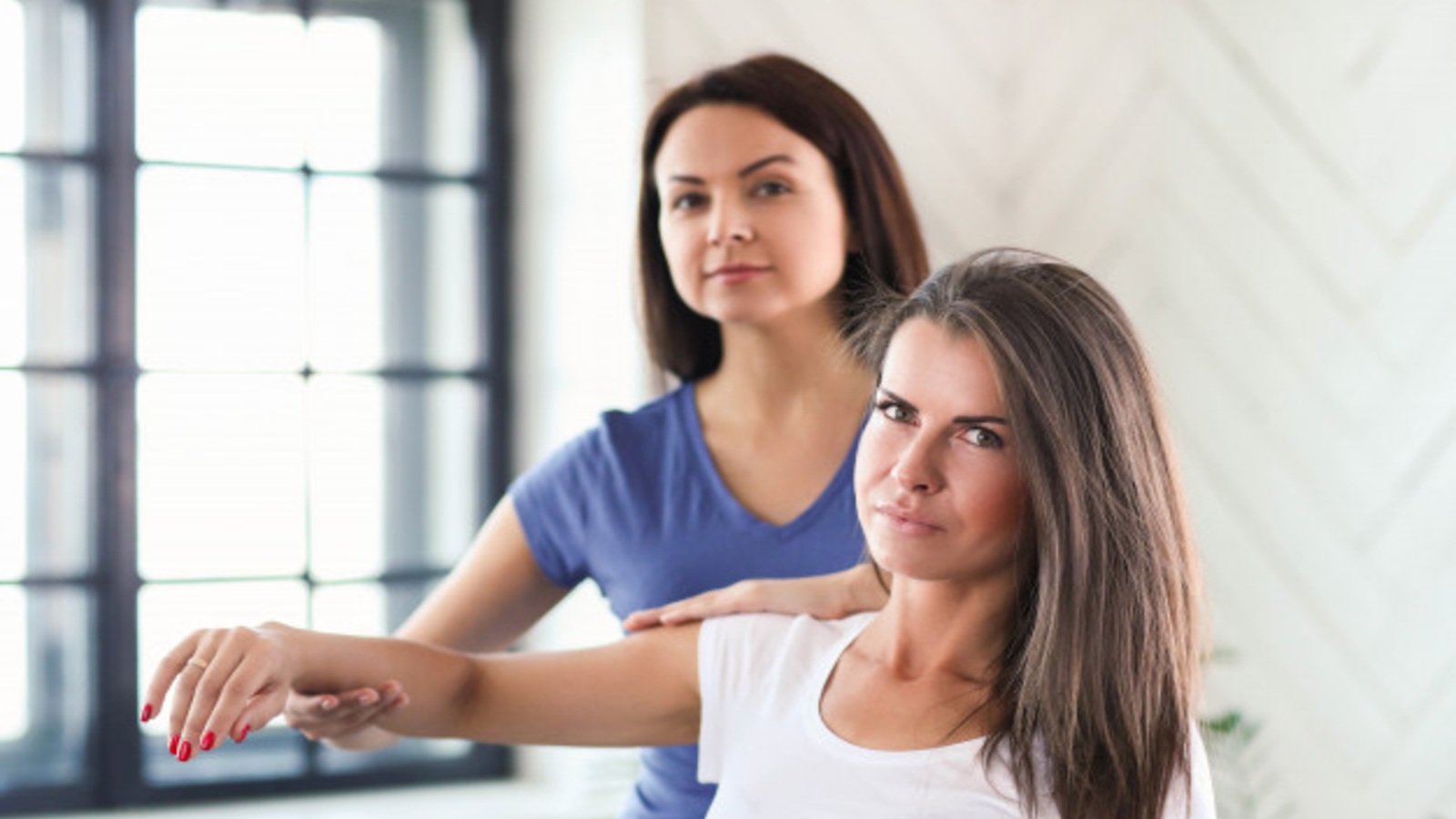 Fitness professional assessing a female client's flexibility