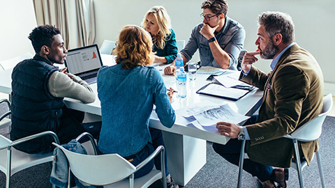 Group discussing a business project around a boardroom table in an office