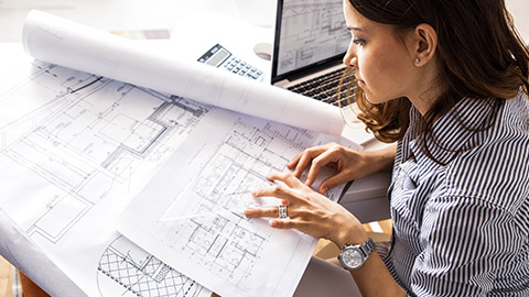 Young female architect looking at plans on a table