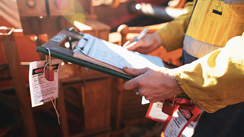 Man on worksite looking at clipboard