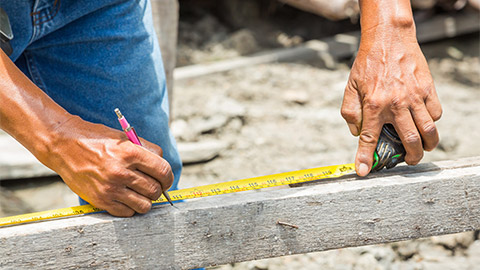 A worker uses a cartridge meter to measure on a construction site.