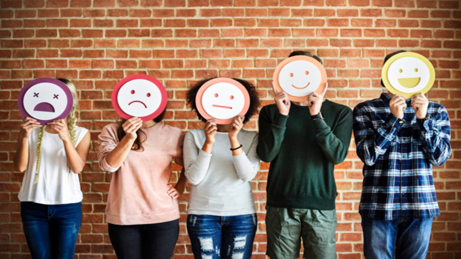 group of young adults holding up emoji icons