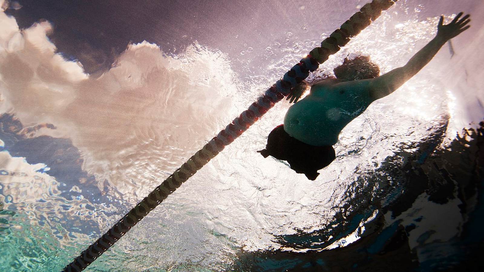 A man with a physical disability swimming in a public pool