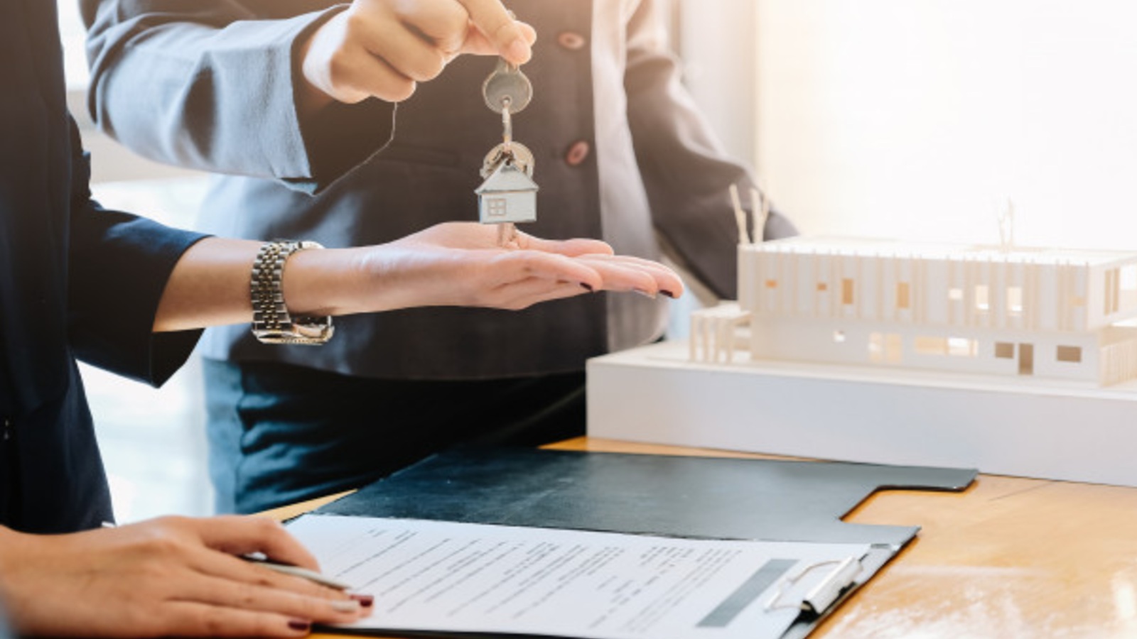 agent handing keys to female signing a contract