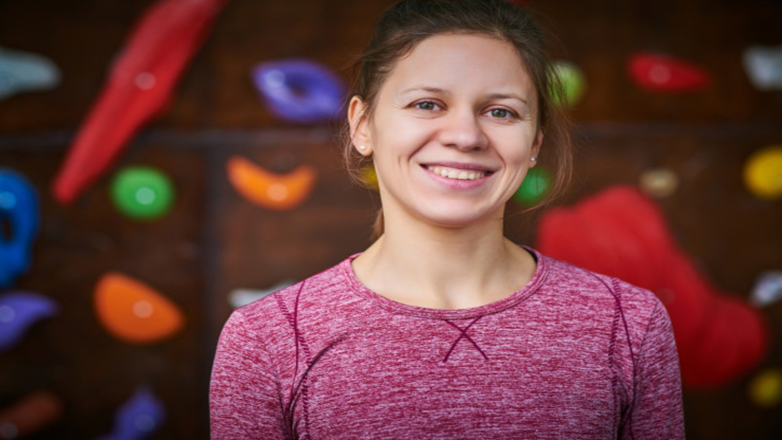 female trainer in front of climbing wall.