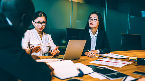 2 female colleagues discussing a project at a boardroom table