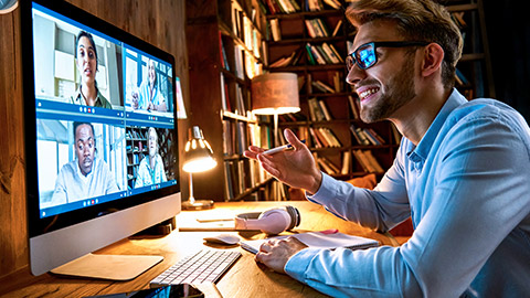 Male sitting at desk holding teleconference with colleagues