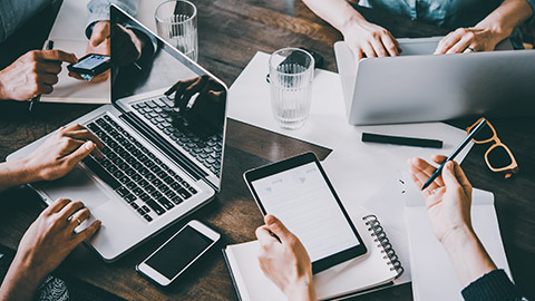 Group of coworkers at a table with multiple technology devices